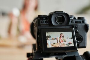 A woman filming a cooking vlog in her kitchen using a digital camera.